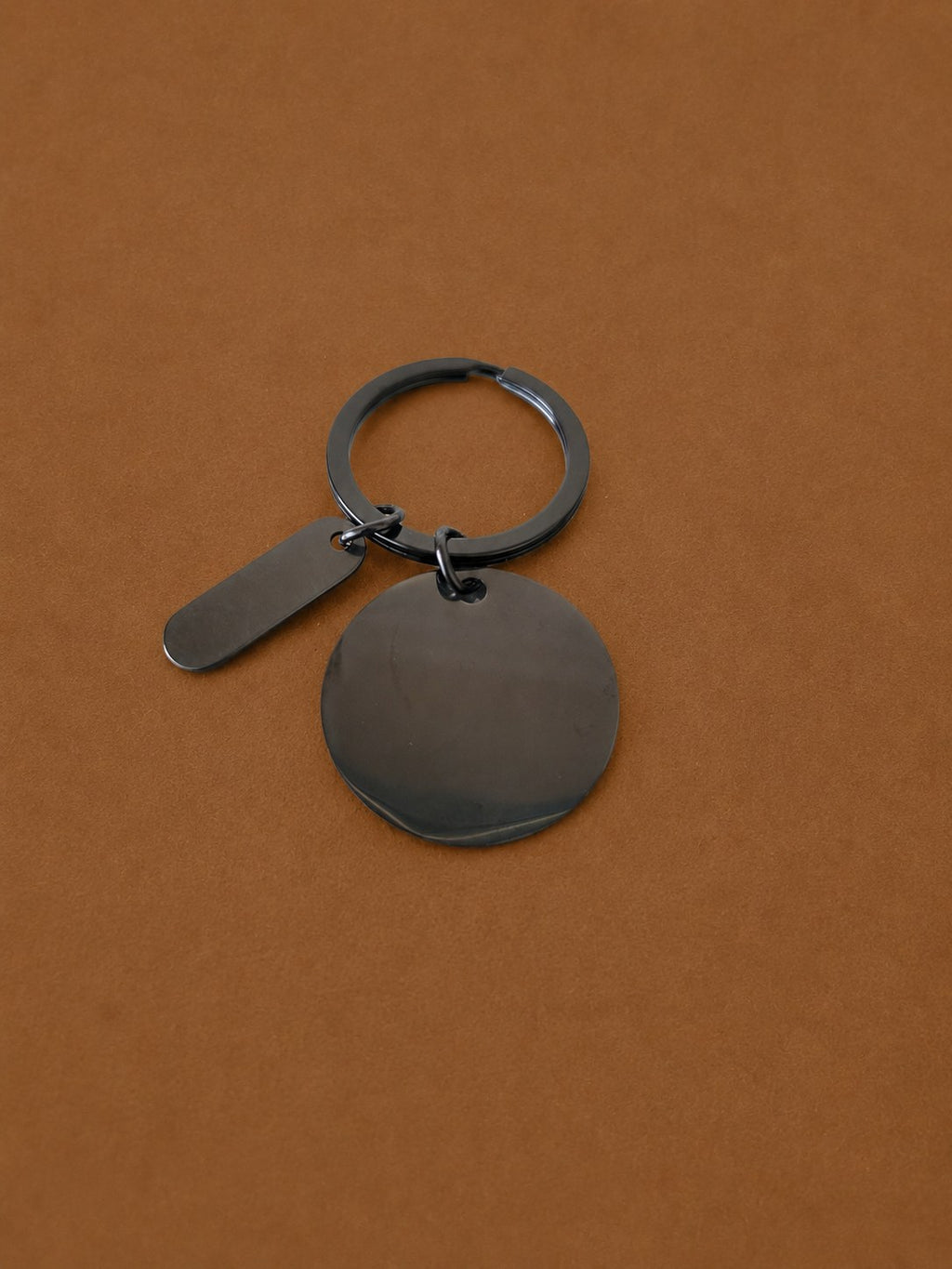 Black round metal keychain with a small tag charm