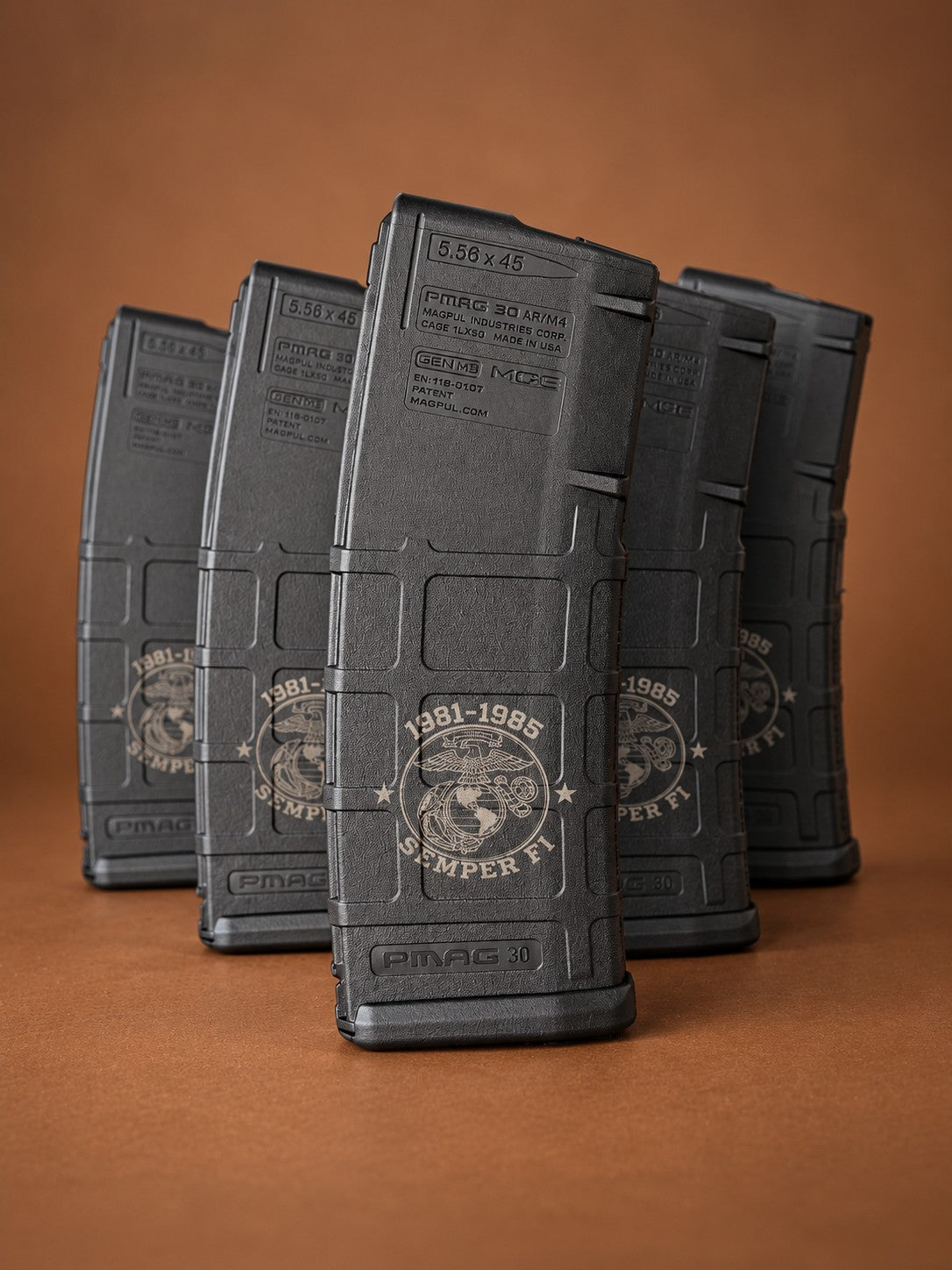 Five black 5.56 PMAG rifle magazines laser engraved with a Marine Corps emblem, 1981-1985 service years and Semper Fi